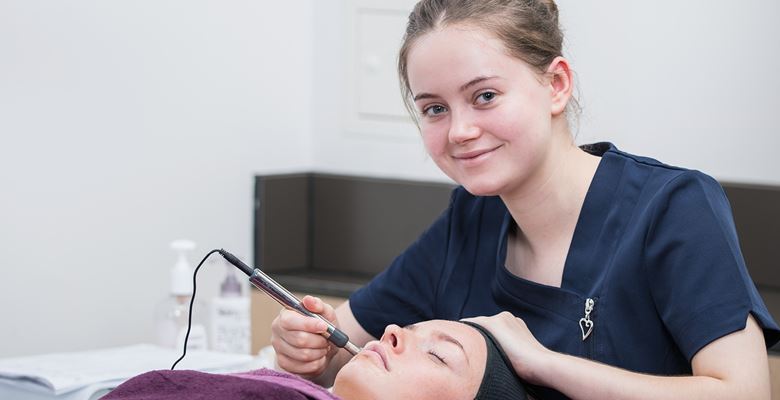 Beauty student preforming a procedure on a client's face. 