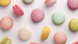 Macrons of various colours spread out on an off white background