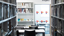 Book shelves in the library, with empty tables and chairs.