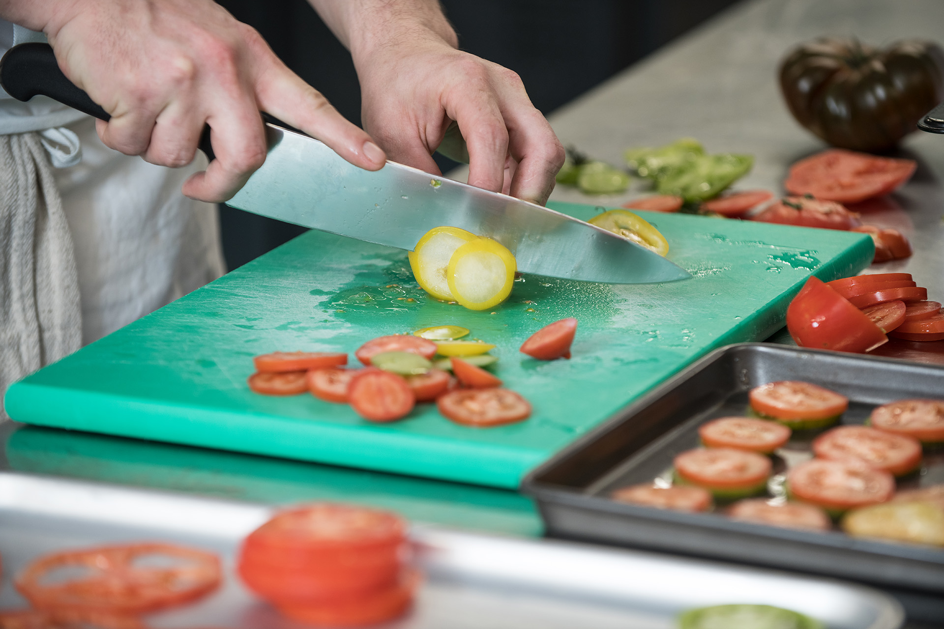 Close up of cookery student chopping vegetables in a training kitchen. 