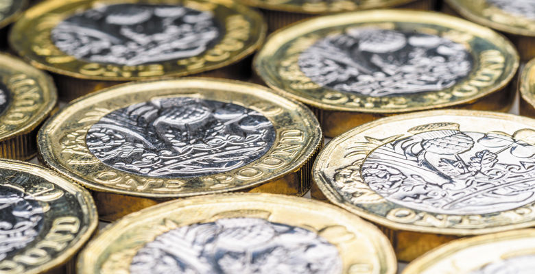 A selection of pound coins all lying flat.