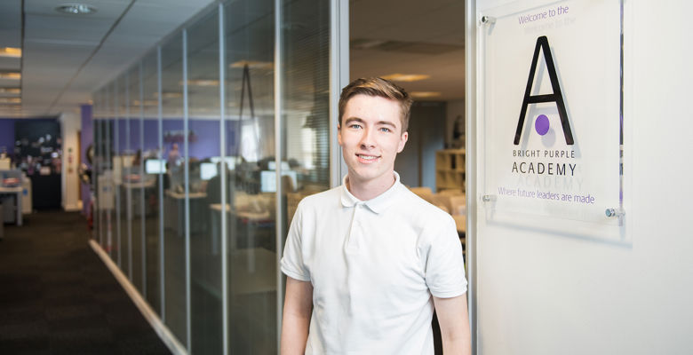 Young student standing next to the sign in an office on their work placement.