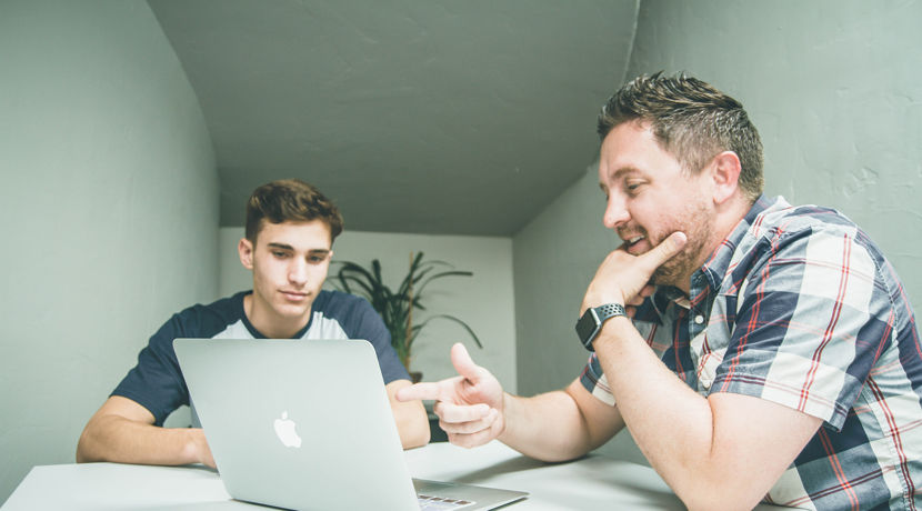 Lecturer is helping a student by showing them something on their laptop.
