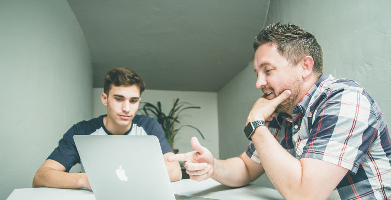 Lecturer is helping a student by showing them something on their laptop.