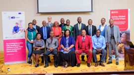 A diverse group of professionals poses for a photo in front of a banner promoting skills development for employment globally.