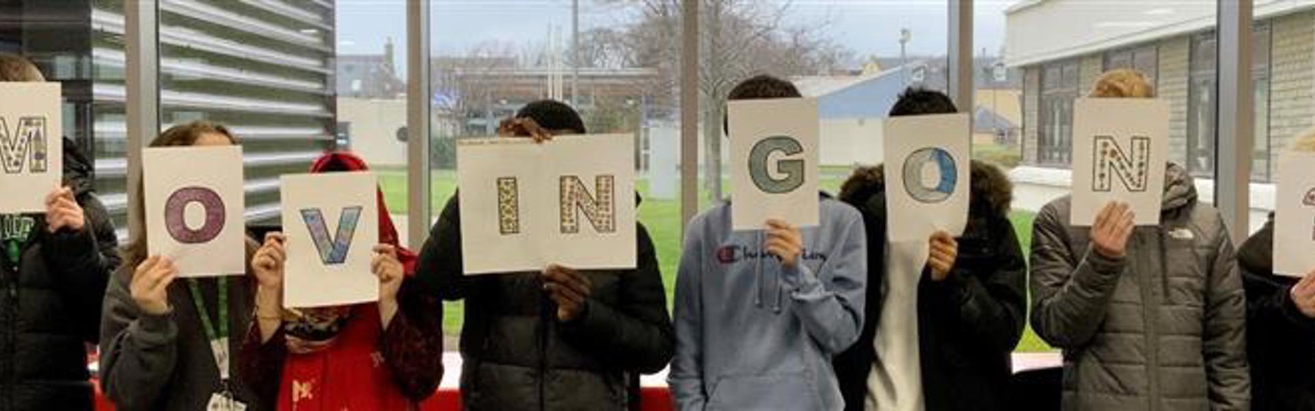 Students holding up letters that spell out Moving On