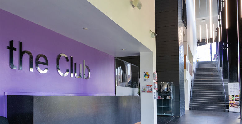 Entrance of the Club gym with a sign on the purple wall that reads 'The Club'