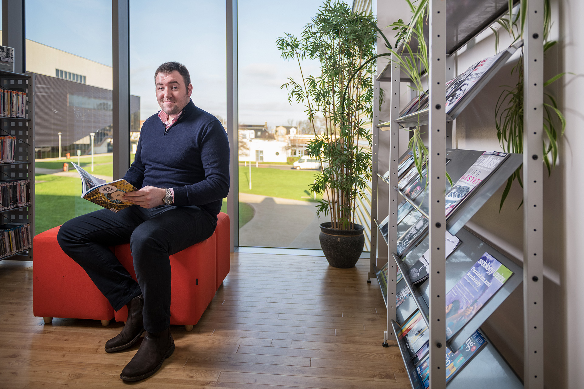 Student sitting in the library reading a book.