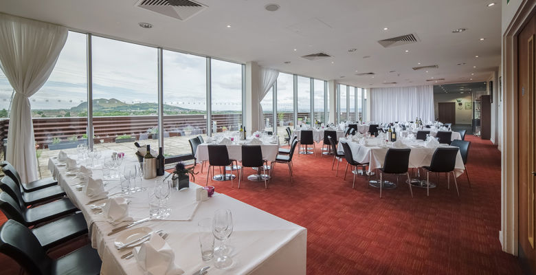 Restaurant at Edinburgh College set up for an event, with white table clothes, glass wear and cutlery on tables.