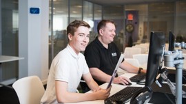 Young student working at a desk in an open plan office during a work placement.