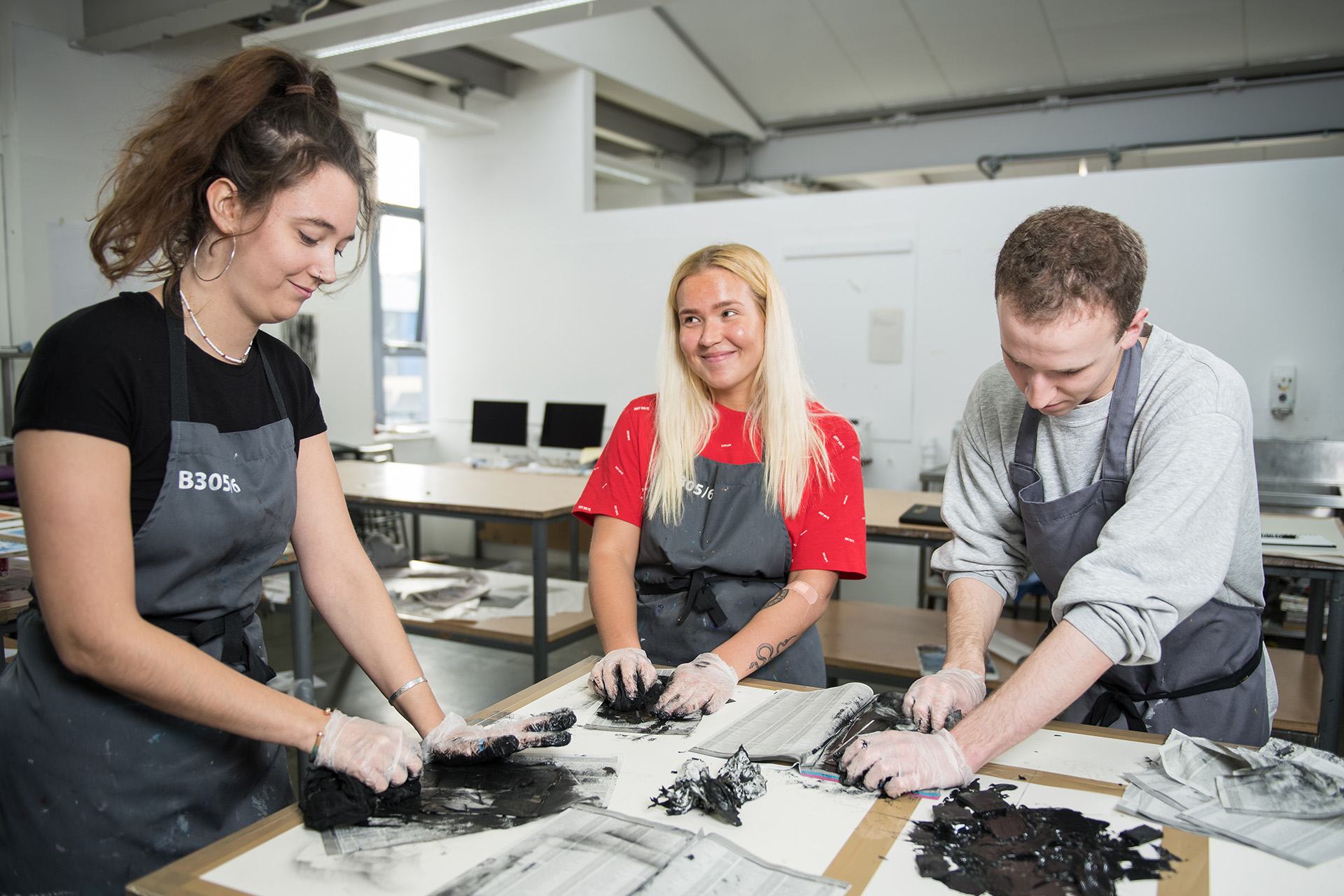 Art students wearing aprons working in their art classroom.