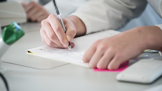 Close up of a person writing notes on a desk.