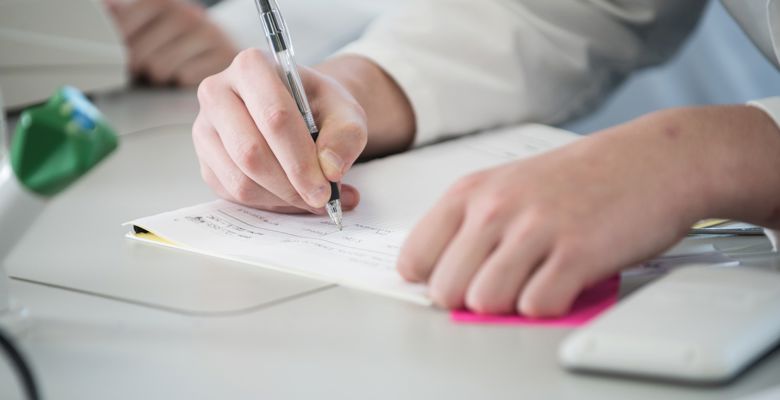 Close up of a person writing notes on a desk.