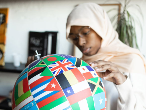 Person holding a globe with lots of different country's flags on it.