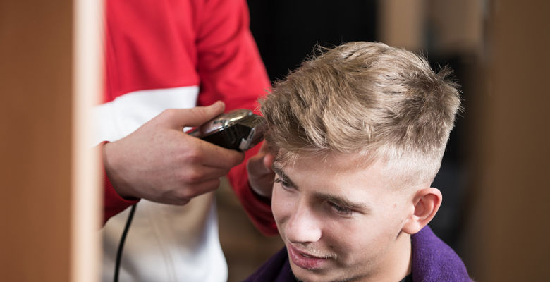 Barbering student clipping a client's hair in the salon.