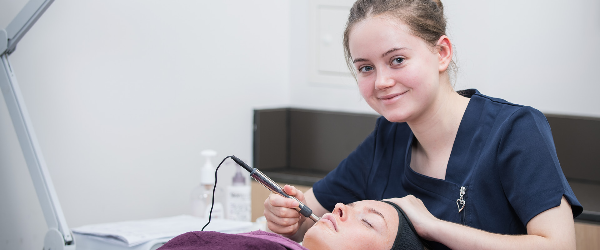 Beauty student preforming a procedure on a client's face. 