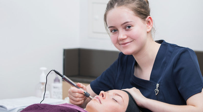 Beauty student preforming a procedure on a client's face.