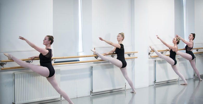 Dance students working on their ballet technique in a dance studio.